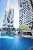 Un edificio de gran altura con una piscina al frente.