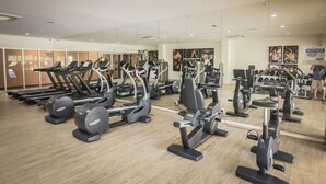 Ein Fitnessstudio mit verschiedenen Cardiogeräten, Krafttrainingsgeräten und einer großen Spiegelwand.