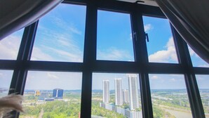 Ein Fenster mit Blick auf hohe Gebäude und Grünflächen.