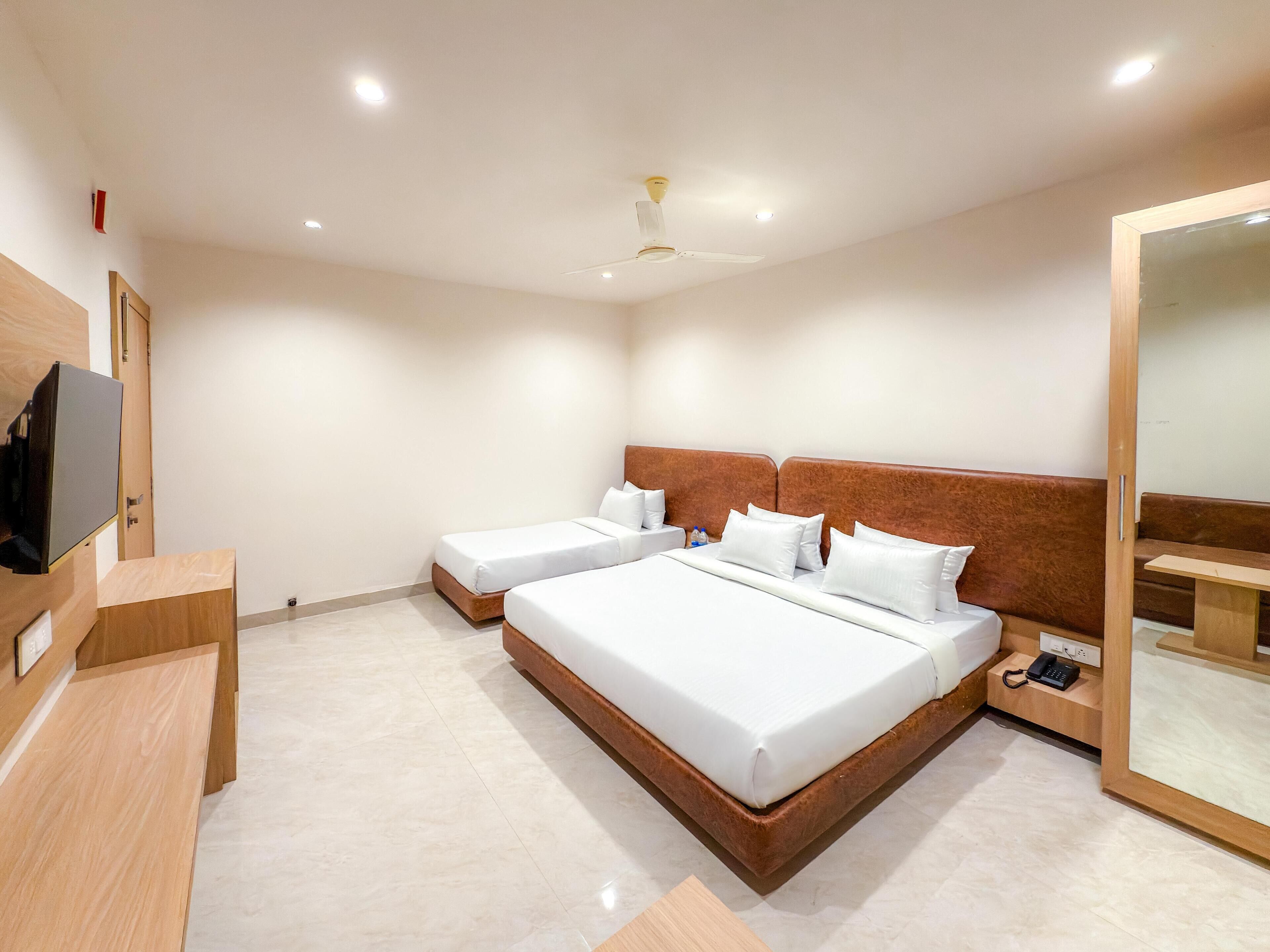 A hotel room with two beds, a wooden headboard, a bedside table with a phone, and a mirror.