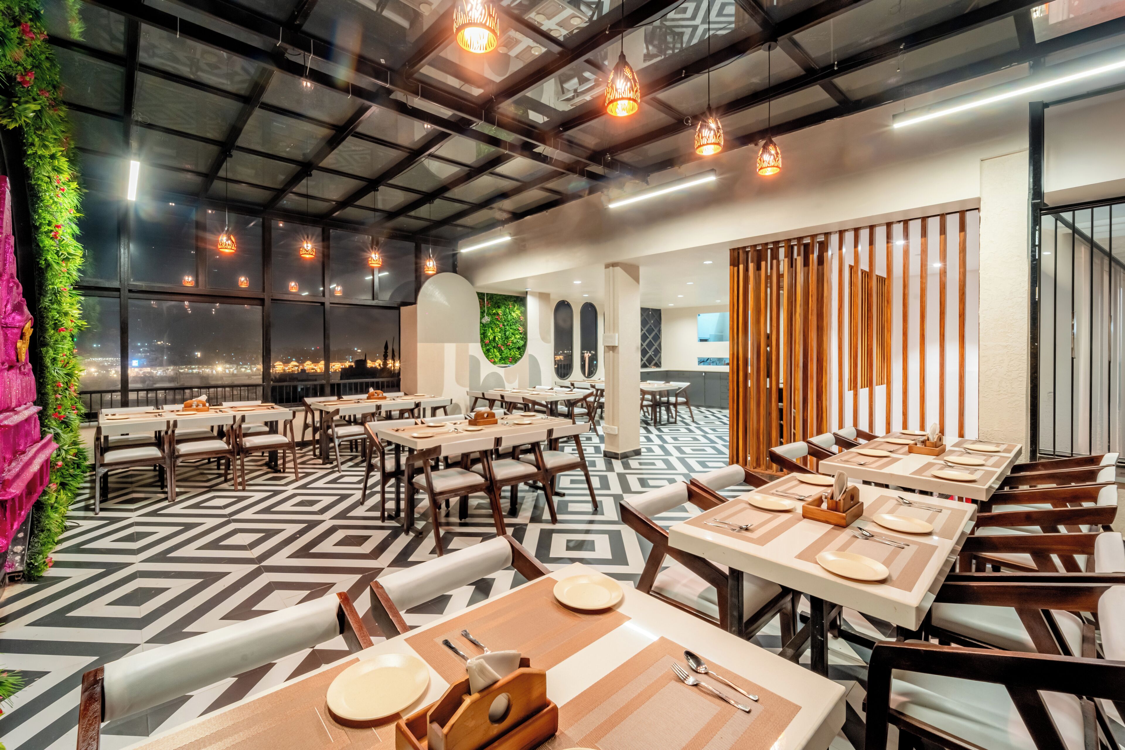A modern restaurant with a geometric patterned floor, wooden tables and chairs, and pendant lighting.