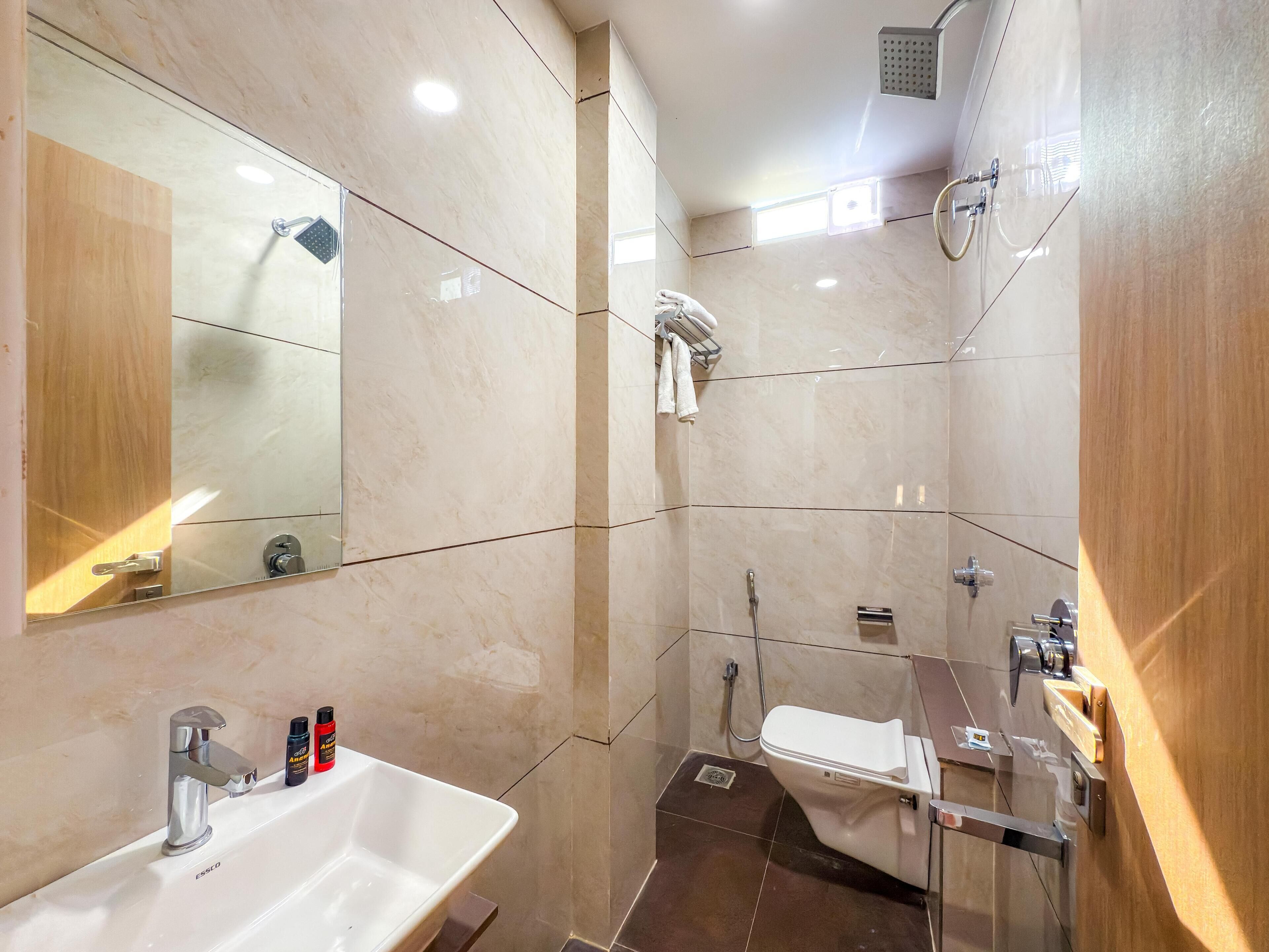 Een moderne badkamer met een wastafel, spiegel, douche en toilet.