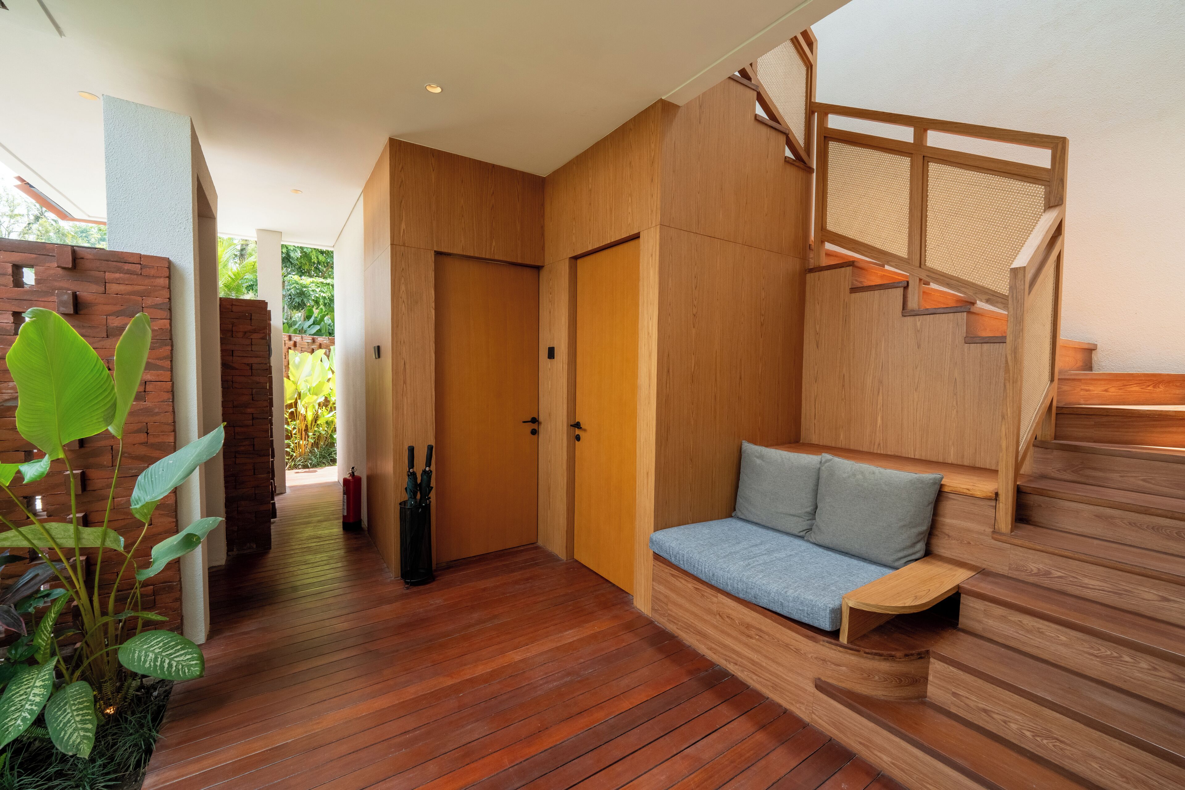 A modern interior with a wooden staircase, a bench, and a plant.
