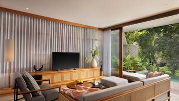 A modern living room with a flat-screen TV, a sofa, a coffee table, and a large window overlooking a lush garden.
