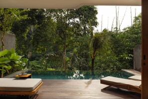 Ein Pool ohne Ende mit Holzterrasse und Liegestühlen, umgeben von üppiger Vegetation.