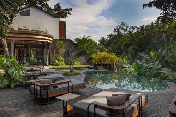 A modern outdoor pool area with lounge seating and a building with large windows. - Alaya Private Estate at Damara Village Ubud (Ubud)