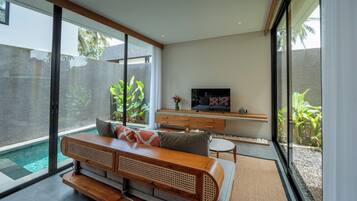 A modern living room with a large glass sliding door, a wooden bench, a TV, and a small table.