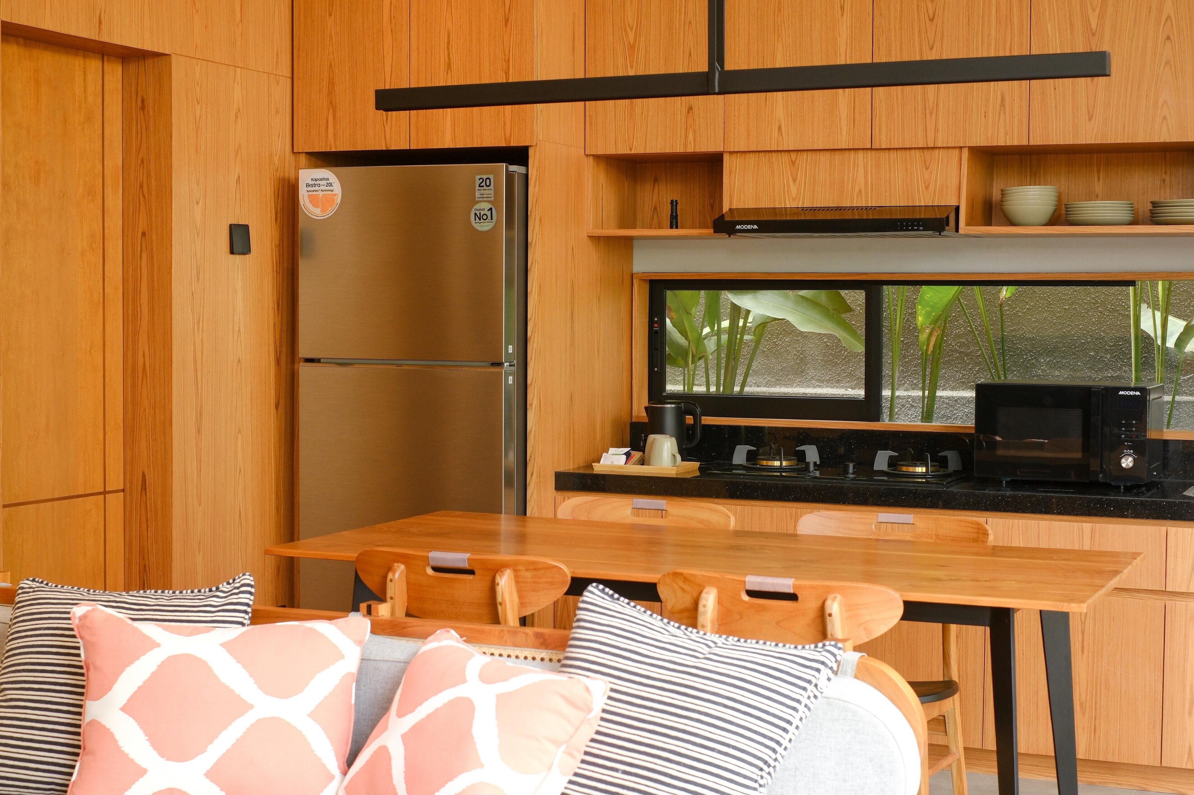 A compact kitchen with wooden cabinets, a built-in microwave, and a refrigerator.