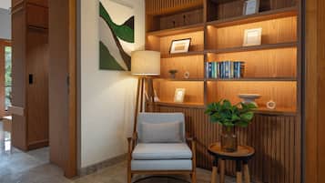 A modern interior with a wooden bookshelf, a comfortable armchair, and a small table with a plant.