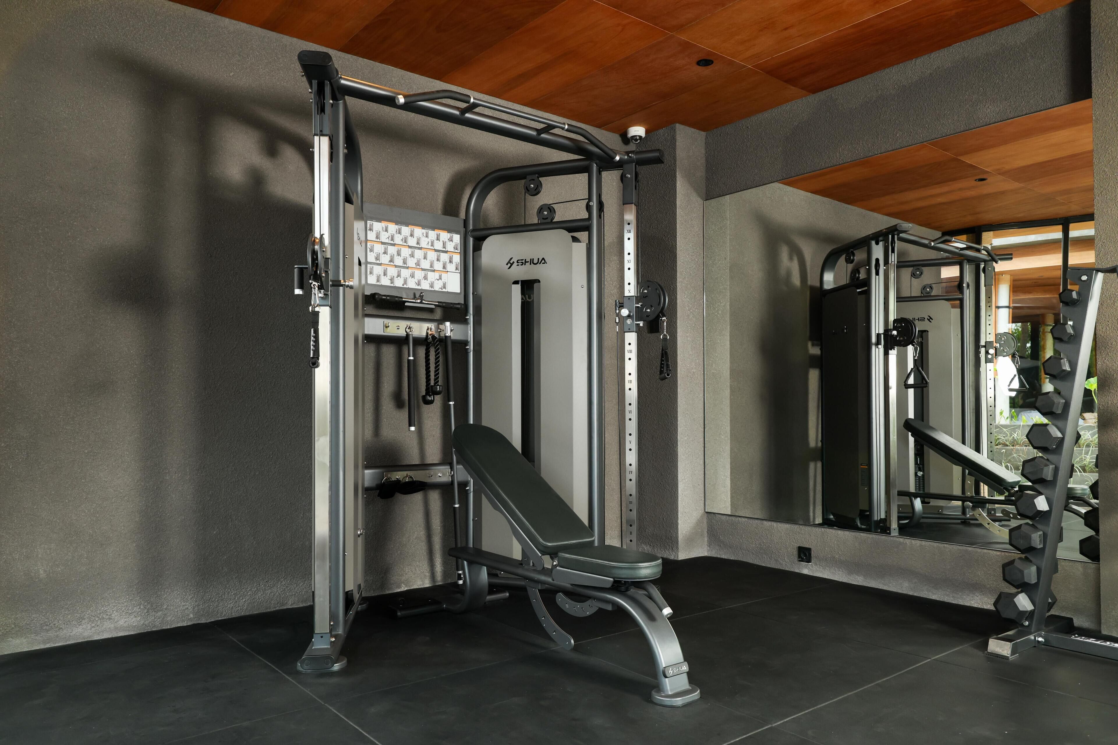 A gym with a bench press, squat rack, and weight plates.