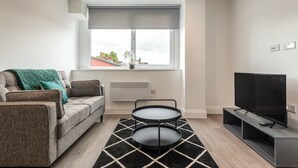 A modern living room with a sofa, a TV, and a two-tiered coffee table.