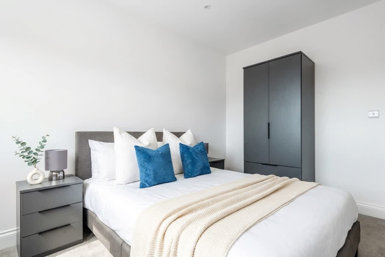 A bedroom with a bed, bedside table, lamp, and wardrobe.