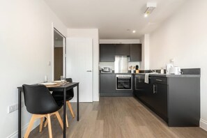 A modern kitchen with dark cabinetry, a central island, and a dining area with two chairs.