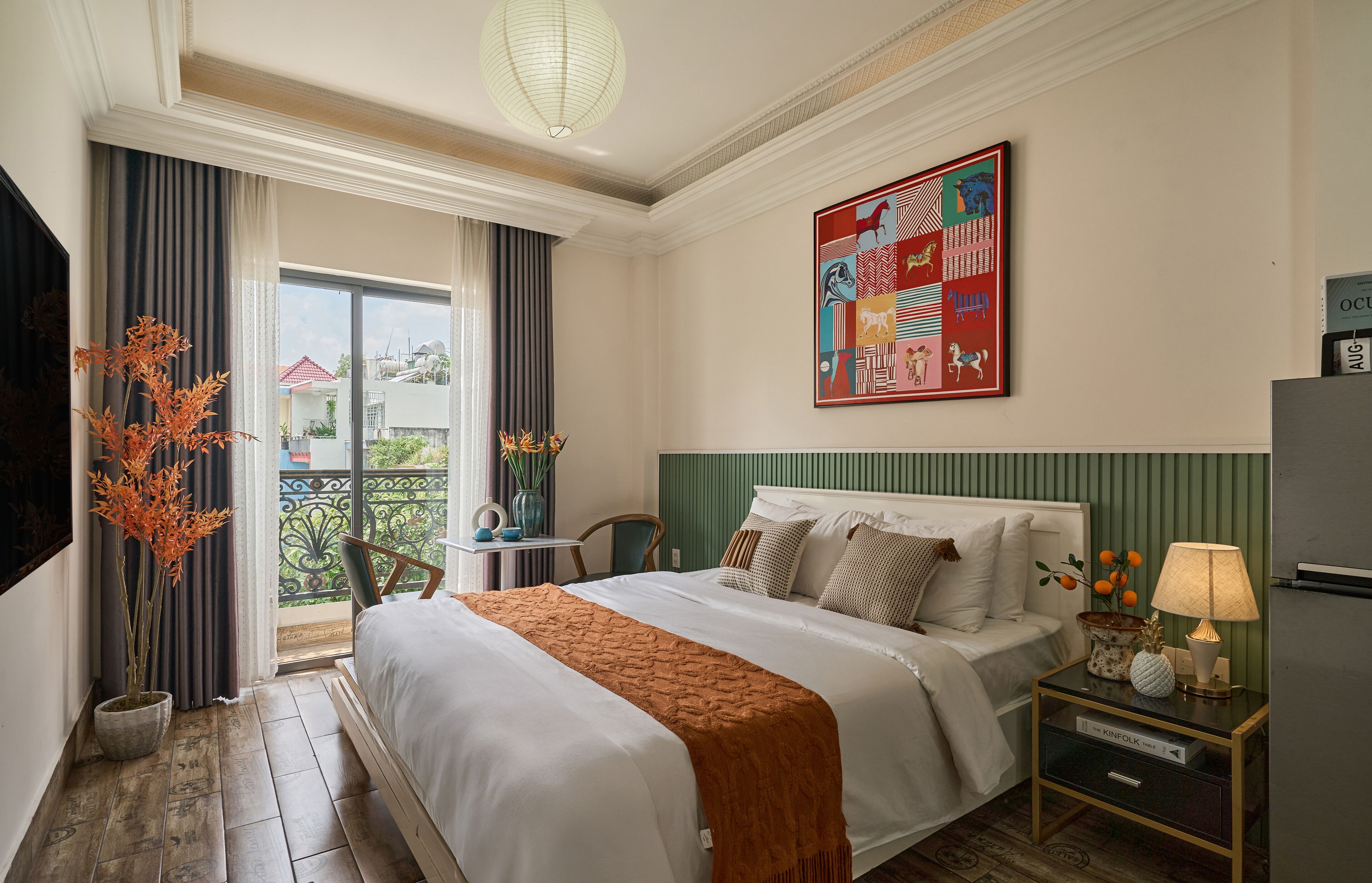 A hotel room with a bed, bedside table, lamp, and a large window with curtains.