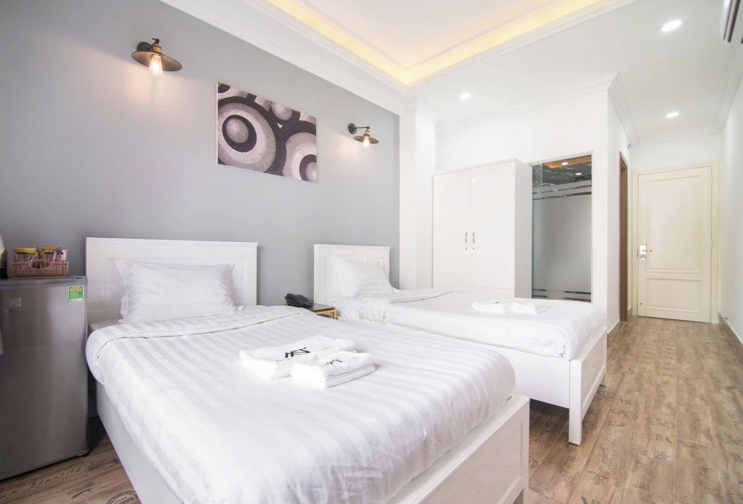 Habitación de hotel con dos camas, un refrigerador, una obra de arte en la pared y un armario.