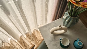 Une table avec une théière, deux tasses et un vase rempli de fleurs.