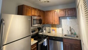 A compact kitchen with stainless steel appliances, wooden cabinets, and a herringbone-patterned backsplash. - 1BR WD Near BJ Hospital Forest Park Zoo (St. Louis)