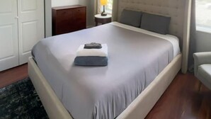A bedroom with a bed, a ceiling fan, a nightstand, a lamp, and a window with curtains. - 1BR WD Near BJ Hospital Forest Park Zoo (St. Louis)