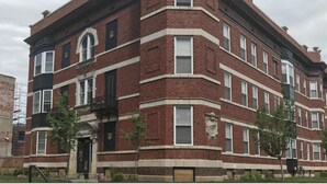 A multi-story brick building with a corner entrance, large windows, and a small balcony. - 1BR WD Near BJ Hospital Forest Park Zoo (St. Louis)