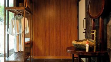 A wooden interior with a tiled floor, a wooden bench, a mirror, and a clothing rack with robes.