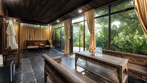A room with a wooden ceiling, large windows, a sofa, a table with fruit and bottles, and a bench. - Trang An Garden Resort (Ninh Binh)