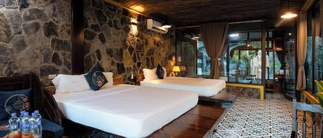 A room with two beds, stone walls, and a patterned floor.