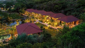 A series of hexagonal buildings with red roofs, surrounded by lush greenery and a small pond. - Trang An Garden Resort (Ninh Binh)