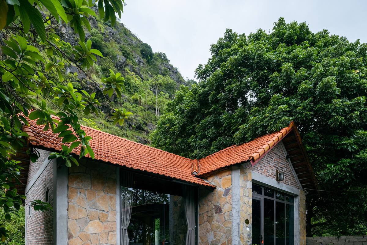 A stone house with a red-tiled roof and a swimming pool.