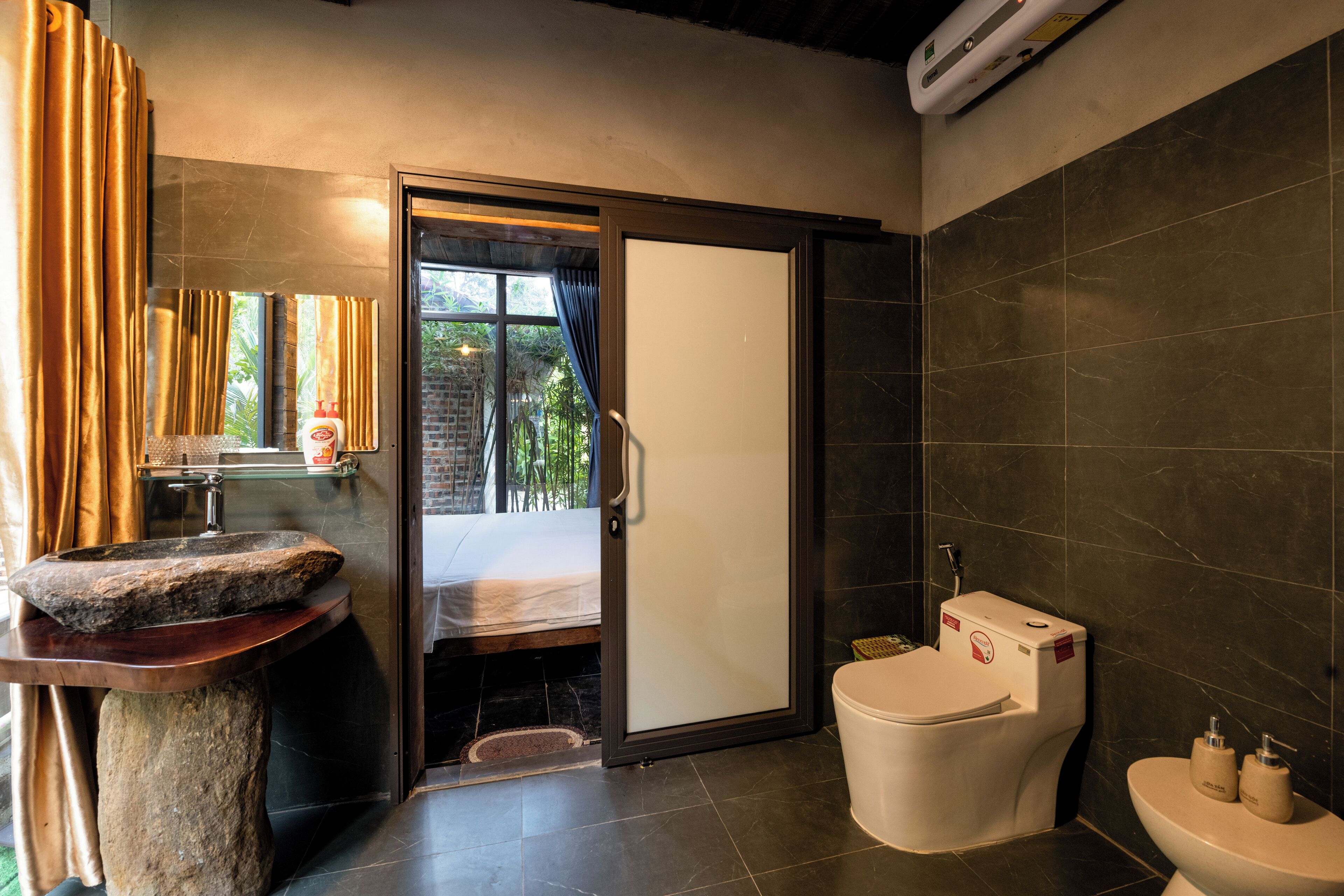A modern bathroom with a stone sink, a glass shower enclosure, and a toilet.