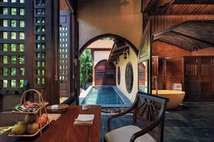 Un espace piscine aménagé avec une table en bois, des chaises et une vue sur la piscine.