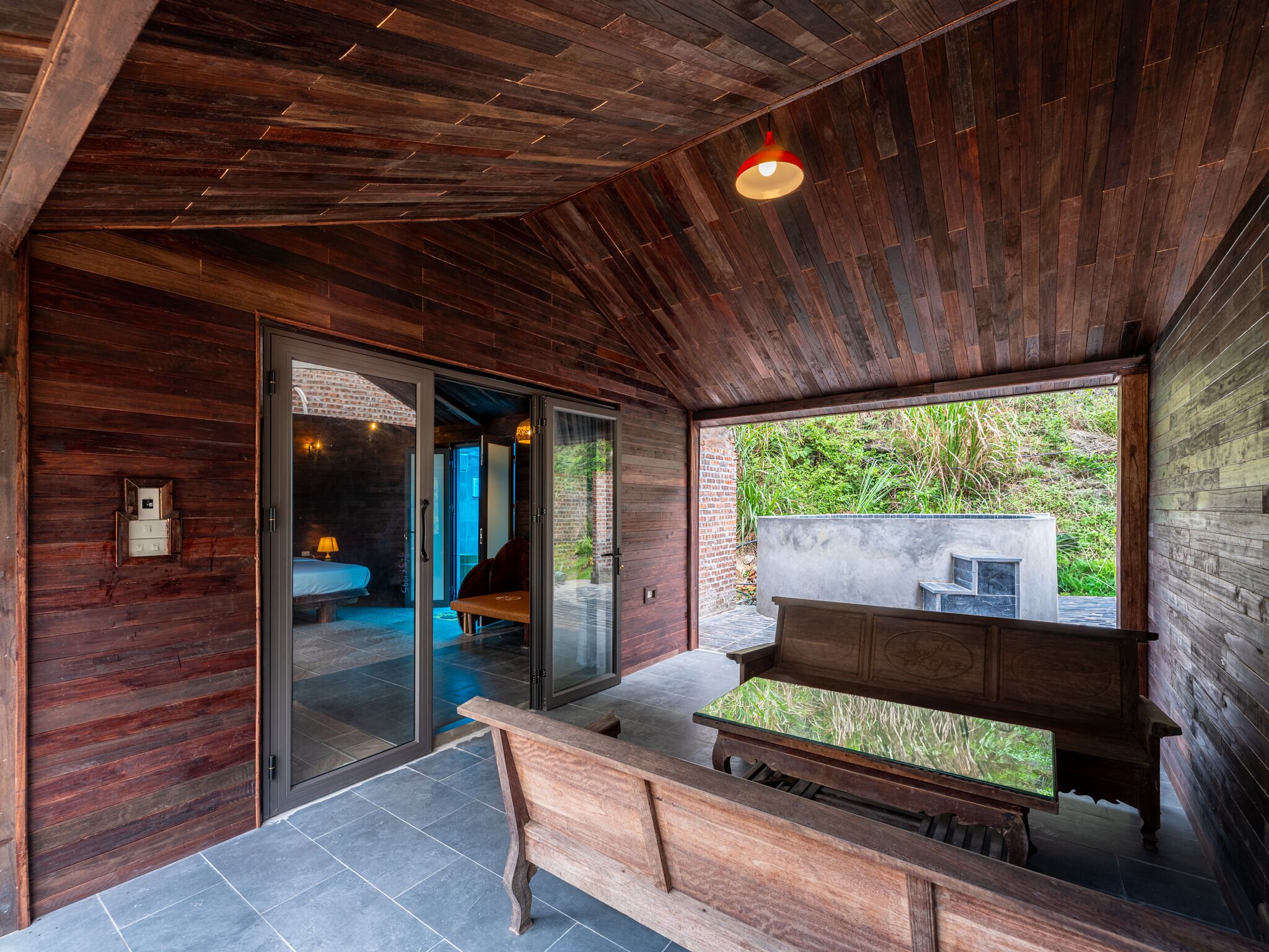 A modern interior with wooden walls, a bench, and a view of greenery outside.