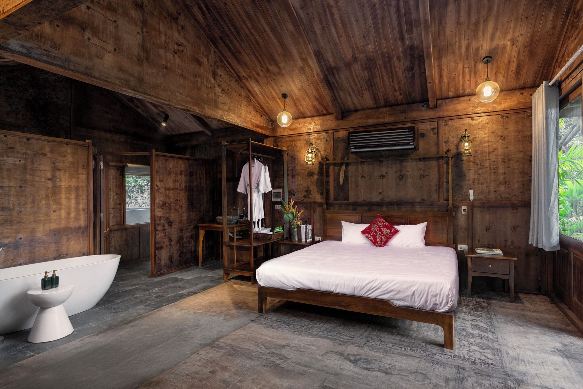 Een slaapkamer in chaletstijl met een groot bed, een witte badkuip en een houten plafond.