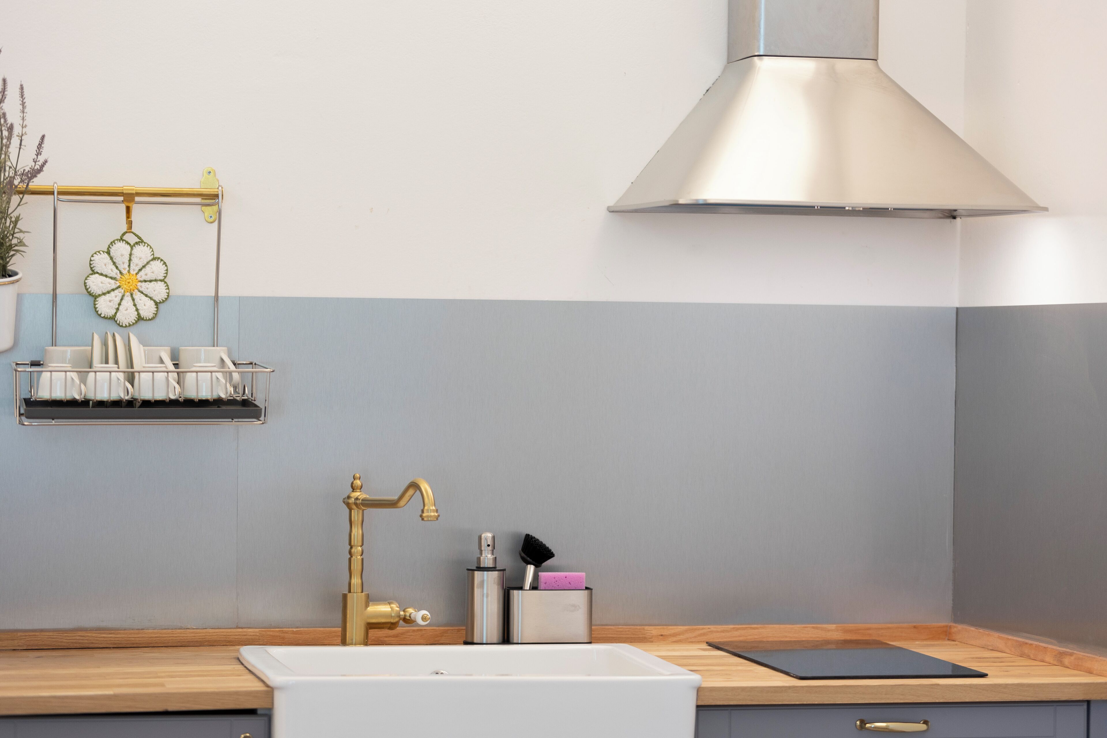 A kitchen with a white sink, a stainless steel range hood, and a wooden countertop.