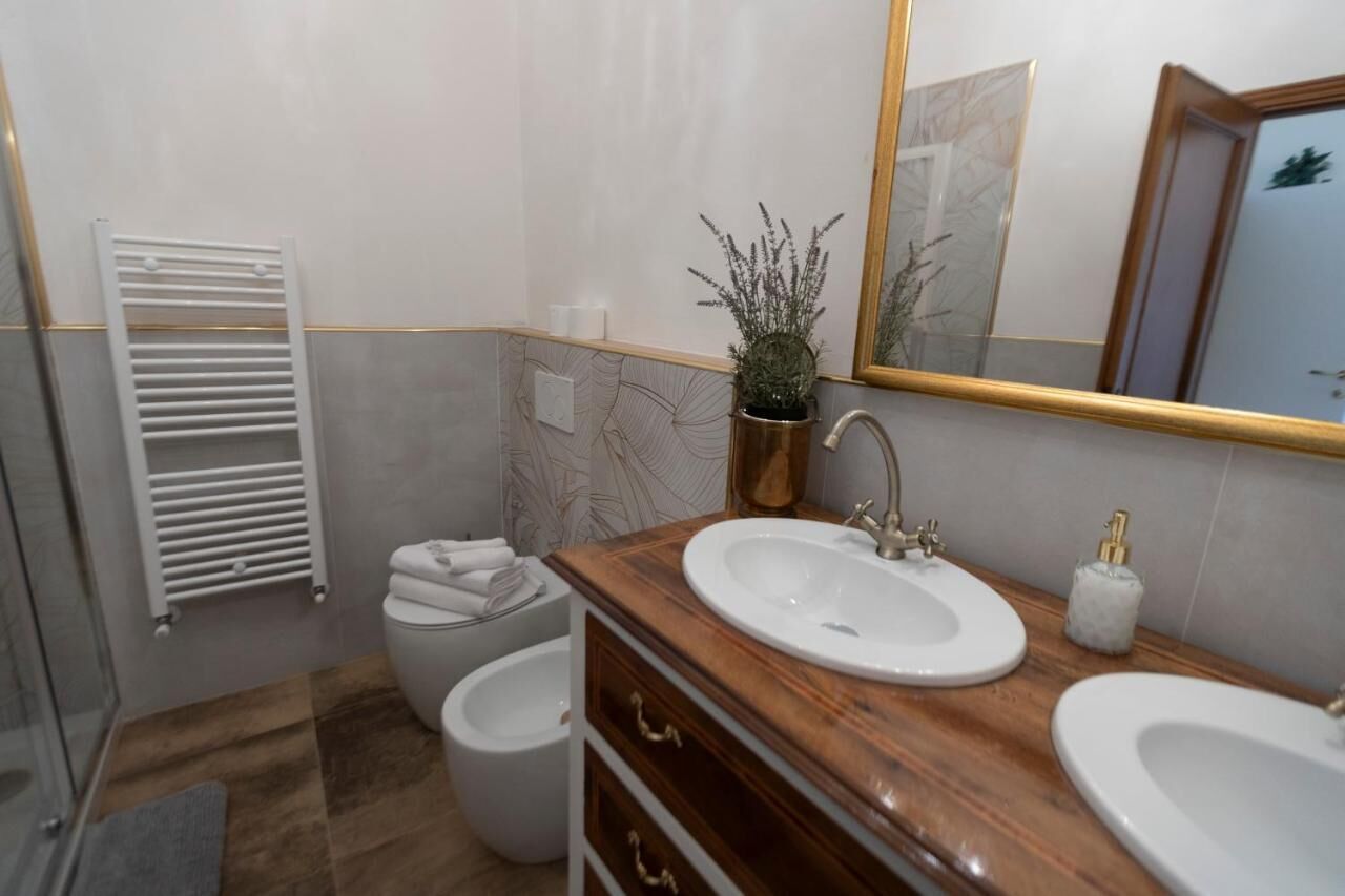 A bathroom with two sinks, a toilet, a shower, and a towel rack.
