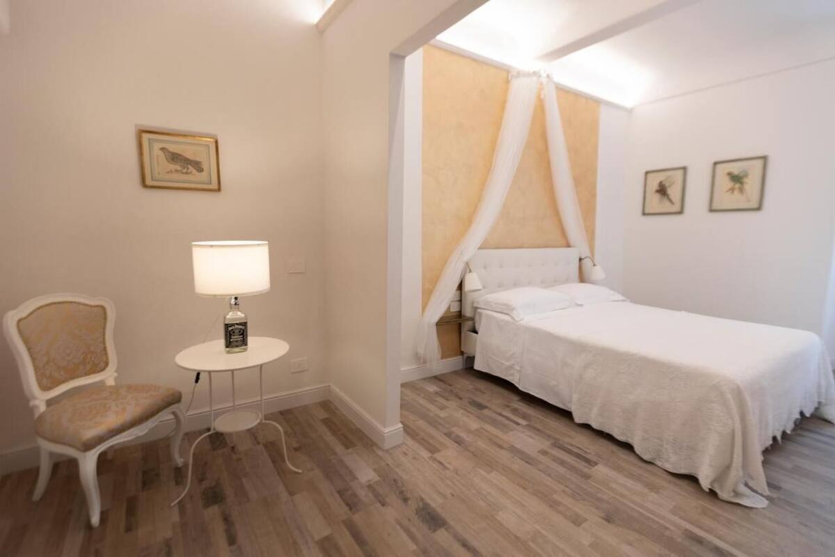 A bedroom with a bed, a chair, a lamp, and a picture on the wall.