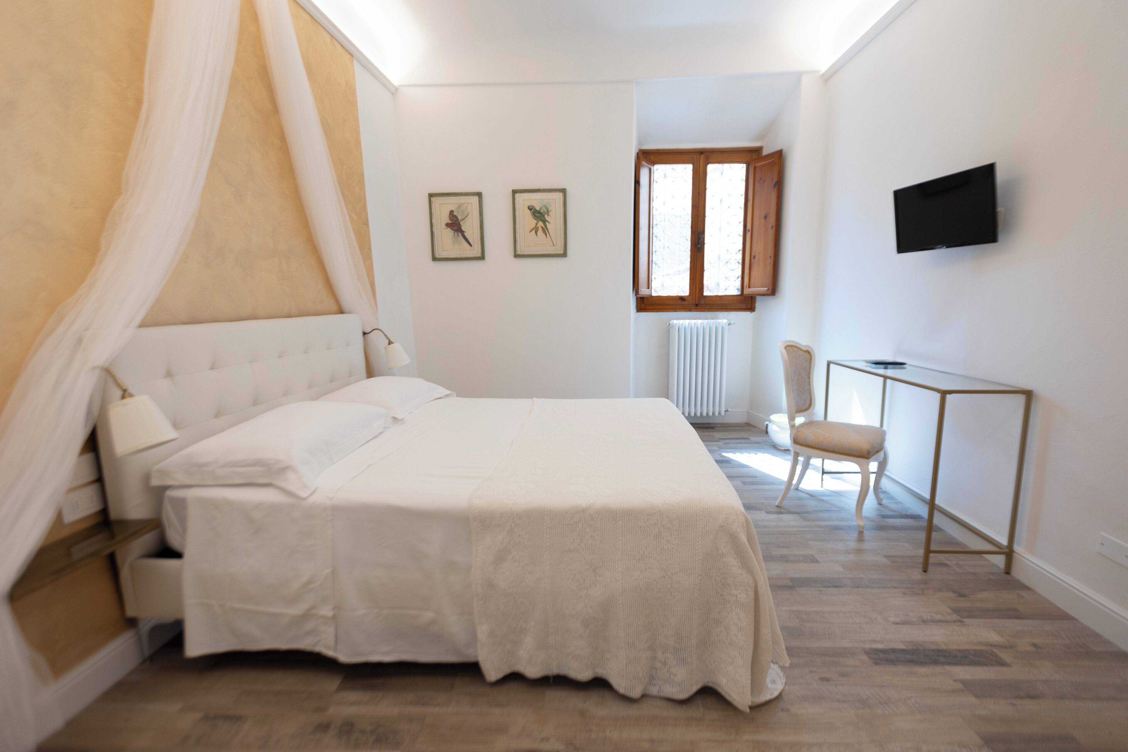 Un dormitorio con cama, escritorio, silla y televisor en la pared.