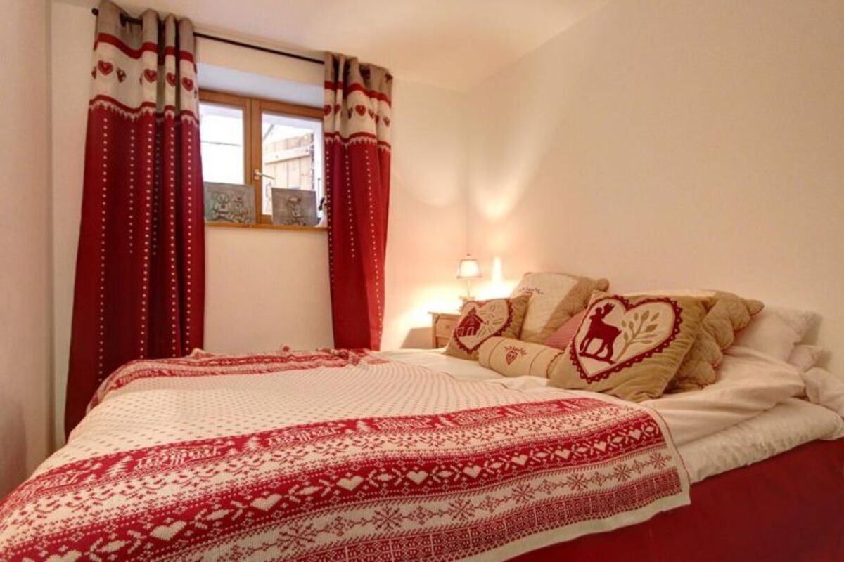 Ein Schlafzimmer mit einem Bett, roten Vorhängen und einem Fenster.