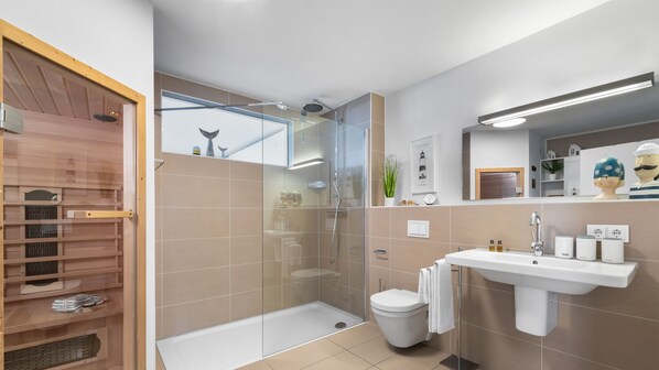 A modern bathroom with a glass shower enclosure, a white sink, and a toilet. - Strandgut - 2 terraces, barbecue, waterfront  sauna, shower, charging station (Olpenitz)