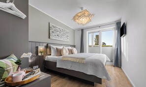 Ein modernes Schlafzimmer mit Bett, Nachttisch und Blick ins Freie.