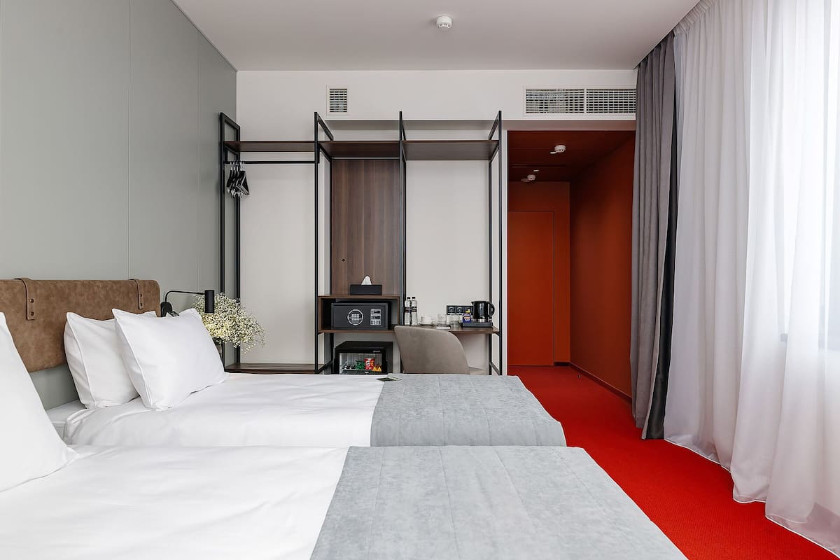Hotellihuone, jossa on sänky, työpöytä, tuoli, pieni pöytä ja vaatekaappi.