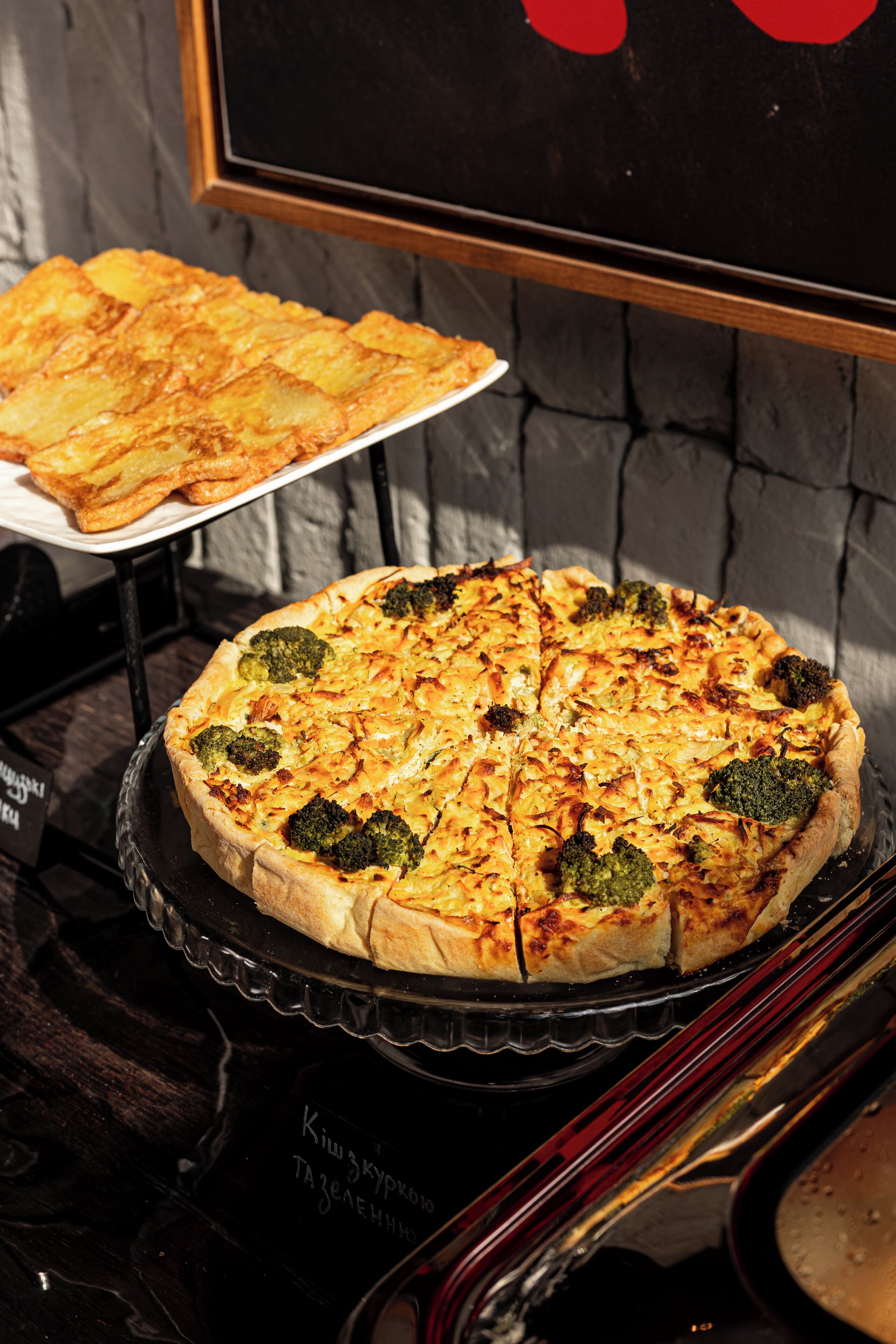 A pizza with broccoli on a black tray.