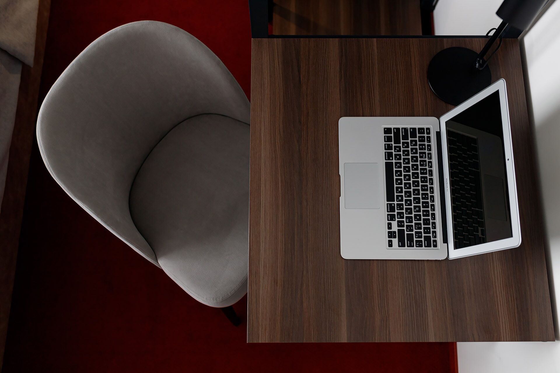 A laptop on a wooden desk with a chair.
