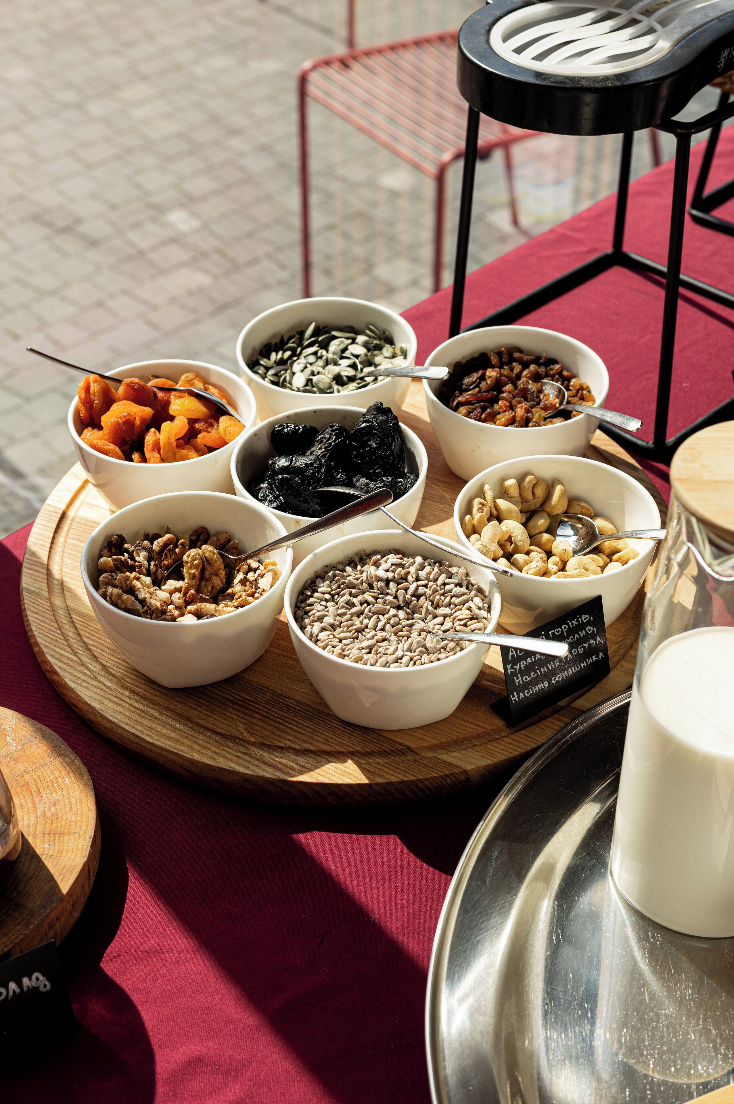 A tray of assorted nuts and dried fruits on a table with a red cloth.