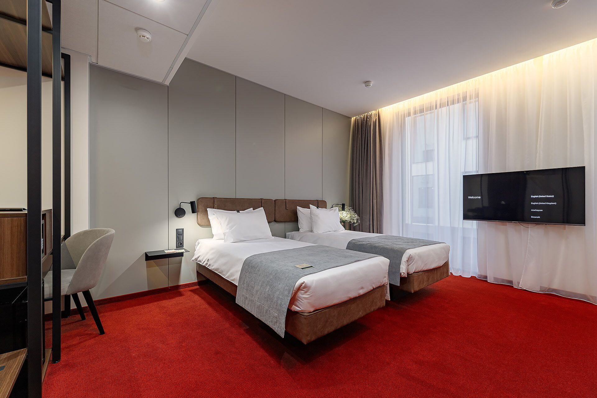 Una habitación de hotel con dos camas, un televisor, un escritorio y una silla.