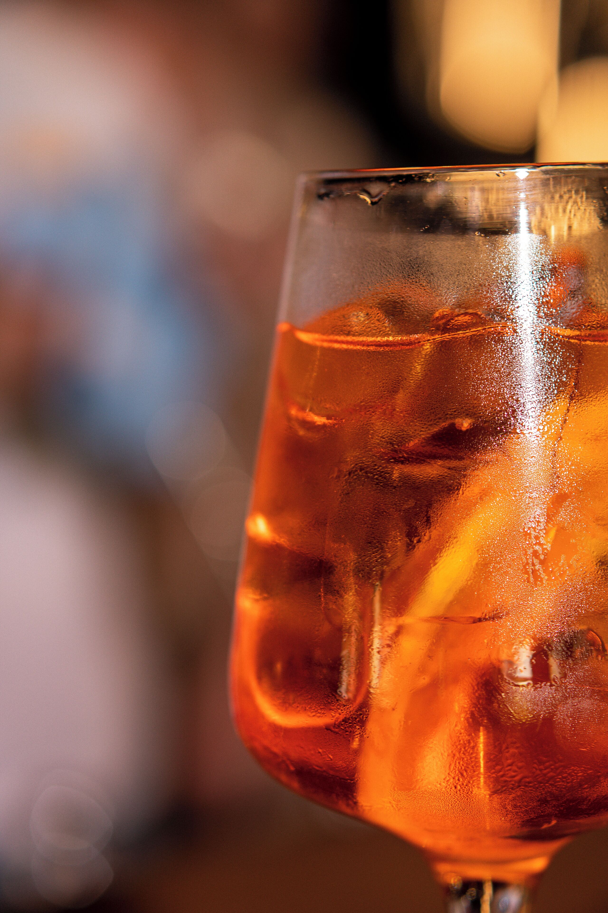 A close-up of a glass with a beverage, ice cubes, and condensation.