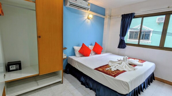 A hotel room with a bed, a wardrobe, an air conditioning unit, and a window with curtains. - Heaven House Sapphire Sky (Patong)