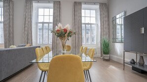 A modern dining area with a glass table, yellow chairs, and a vase of flowers. - Georgian Gem in the New Town (Edinburgh)