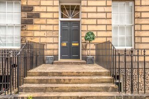A building with a double door, stone steps, and a small potted plant.