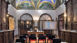 A lecture hall with arched ceilings, wooden desks, and black chairs with red cushions. - La Nova Bed and Museum (Naples)
