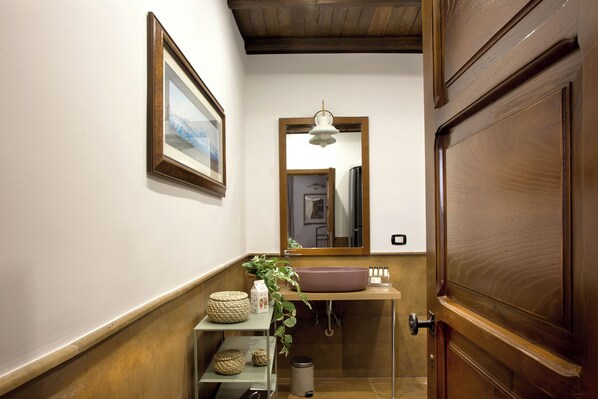 A bathroom with a wooden door, a sink, a mirror, and a framed picture on the wall. - La Nova Bed and Museum (Naples)
